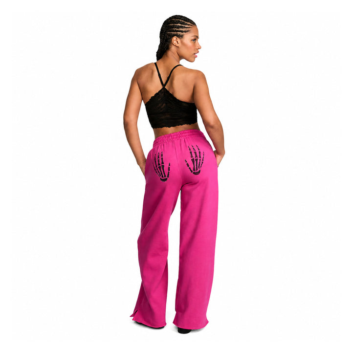 Pink wide-leg pants with black skeleton-hand back graphics on model, back view