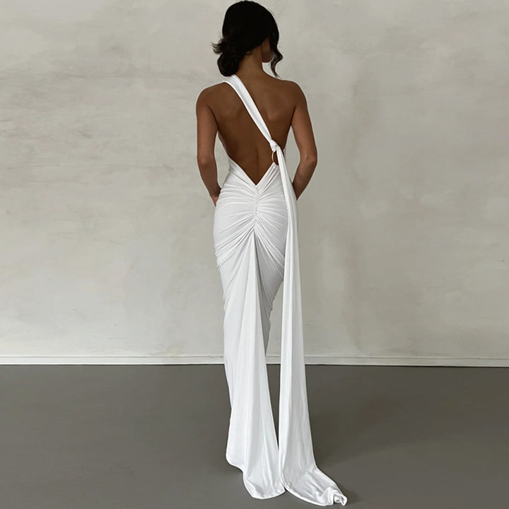 White one-shoulder maxi dress showing the open back, ruching, and trailing sash